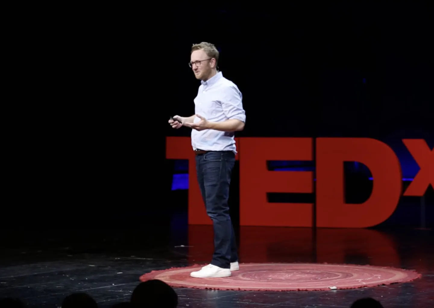 Thomas Schulz steht auf einer Bühne und hält einen Vortrag. Im Hintergrund ist das TEDx Logo zu sehen.